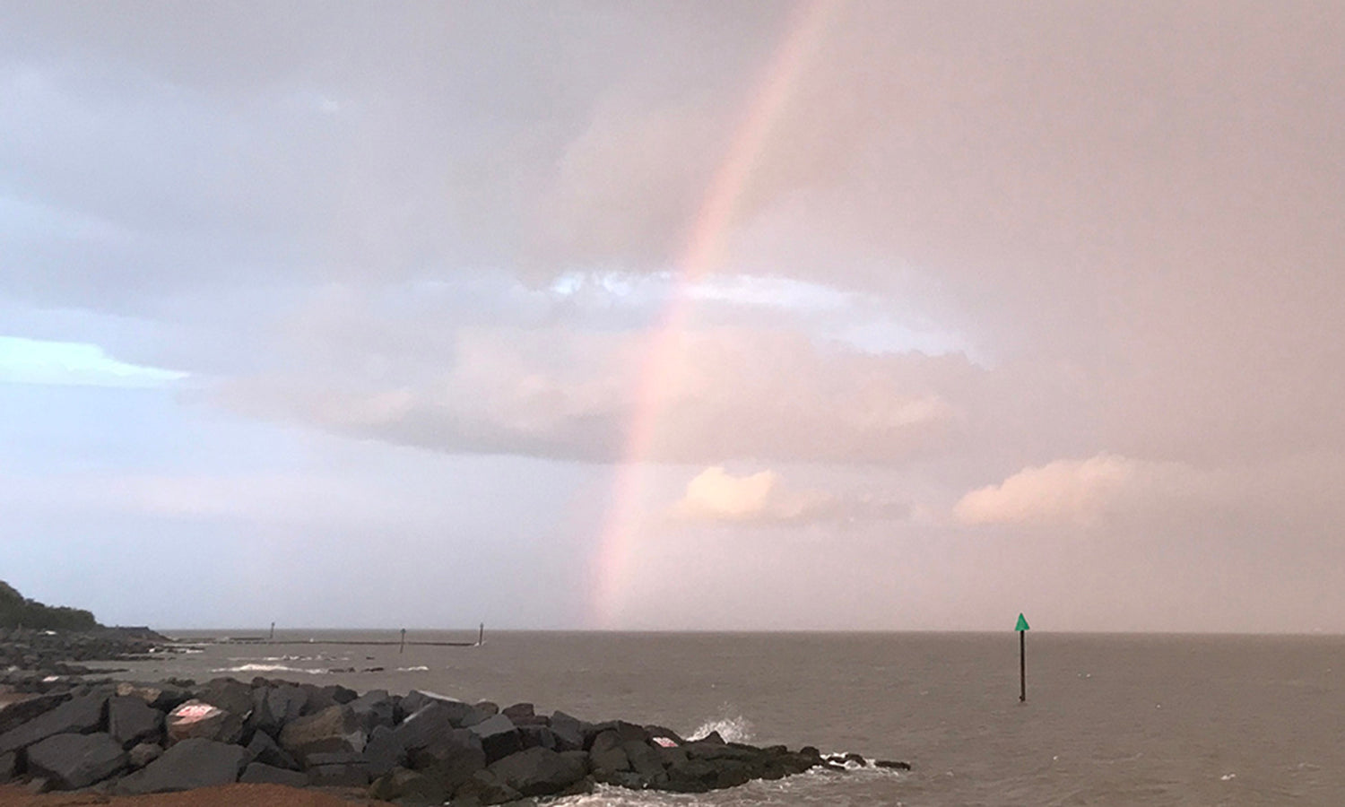 A rainbow over a calm sea looking out from Felixstowe beach in Suffolk